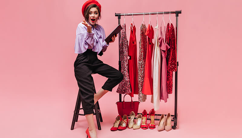 Woman standing next to a clothing rack with various clothes