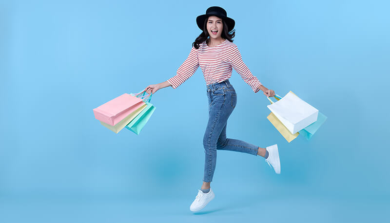 Woman holding shopping bags and jumping
